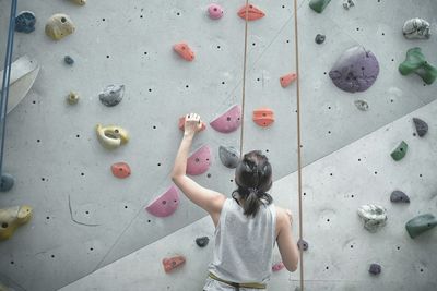 Rear view of woman climbing on wall
