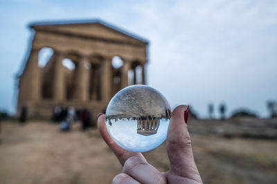 Close-up of woman hand holding crystal ball against old building