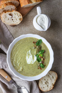 Broccoli cream soup served with mint, cream, seeds and bread. healthy vegetarian food concept. 