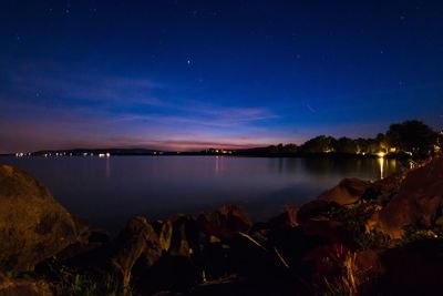 Scenic view of lake against clear sky at night