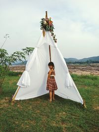 Portrait of girl standing by tent on land