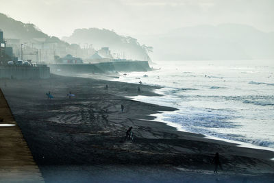 Scenic view of sea and beach against sky in foggy morning