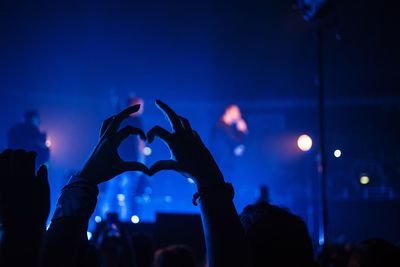 Friends making heart shape at music concert