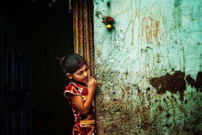 Cute girl standing on house doorway