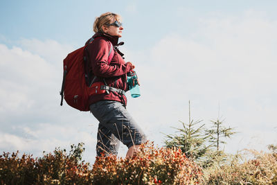 Woman with backpack hiking in mountains. woman standing on top of hill admiring mountain landscape