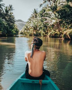 Rear view of man on lake against trees