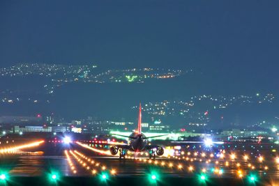 Airplane on runway at illuminated airport during night