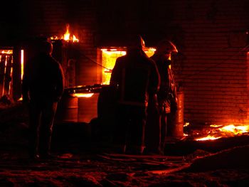 Silhouette people against illuminated fire at night