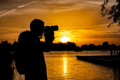 Silhouette man  photographing at sunset