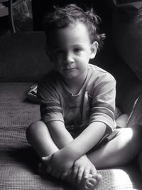 Full length portrait of boy sitting on sofa at home