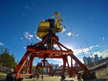 Low angle view of crane against sky in city