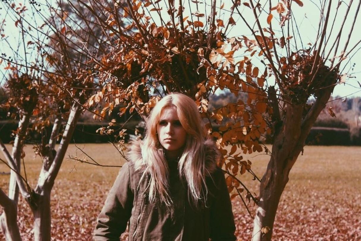 PORTRAIT OF YOUNG WOMAN STANDING BY TREE