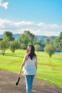 Rear view of woman standing on field against sky