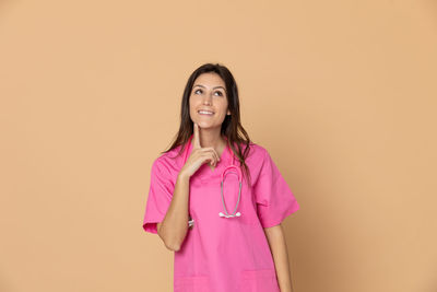 Portrait of a smiling young woman against pink background