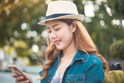 Portrait of smiling young woman using mobile phone outdoors