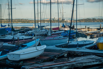 Sailboats moored on harbor against sky