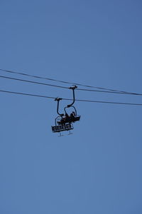 Low angle view of overhead cable car against clear blue sky