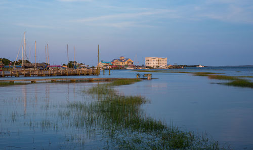 River and buildings against sky at dusk