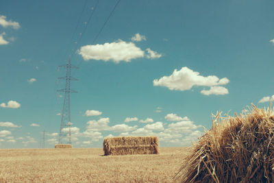 Hay bales on field against sky