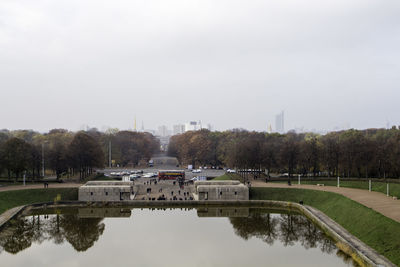 Reflection of trees in city against sky