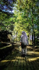 Rear view of woman walking on footpath