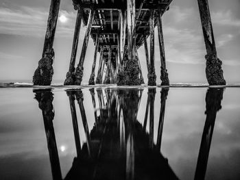 Reflection of pier on sea against sky