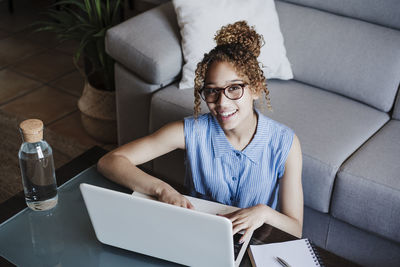 Young woman using mobile phone while sitting on sofa