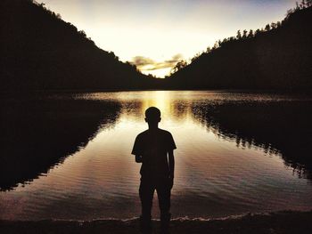 Silhouette of people standing on beach at sunset