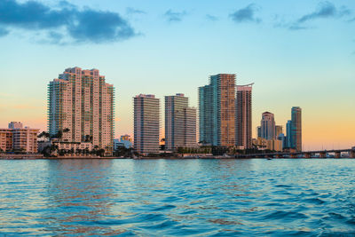 Sea by city buildings against sky