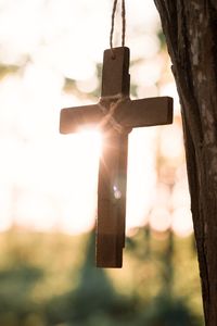Close-up of cross hanging on tree against sky