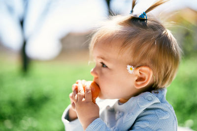 Side view of girl eating food while sitting outdoors