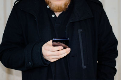 Midsection of man holding mobile phone