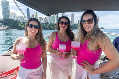 Female friends on top of a boat against the sea in the background. 