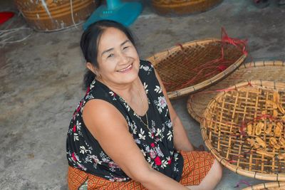 Portrait of smiling woman sitting by baskets at store