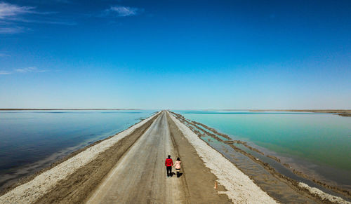 Rear view of people riding on sea against blue sky