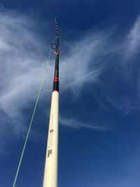 Low angle view of fishing rod against blue sky