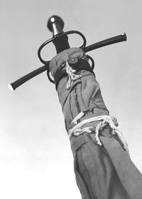 Low angle view of man holding metal against sky