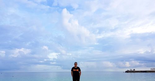 Man standing in sea against sky