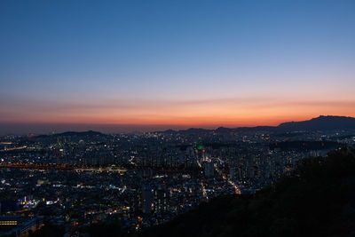 Mountain view of illuminated city against sky at sunset