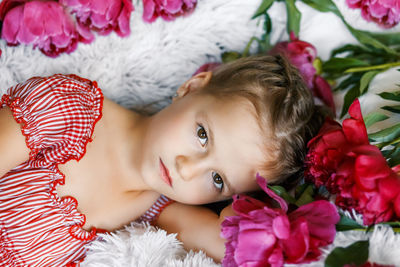 Portrait of girl lying amidst flowers on bed