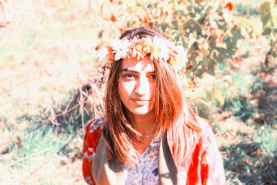 Portrait of young woman with brown hair wearing flower wreath on sunny day