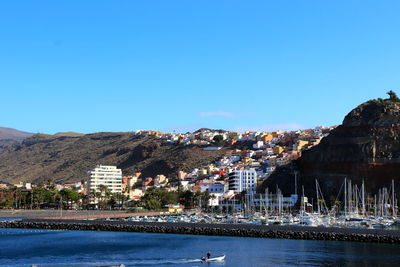 City at waterfront against blue sky