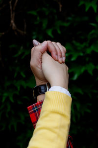 Cropped image of couple holding hands against plants