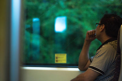 Side view of woman looking through window