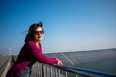 Young woman wearing sunglasses against clear blue sky