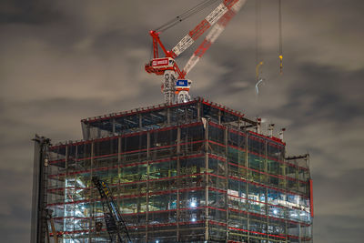 Low angle view of crane in building against sky