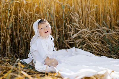 Sweet eight-month-old baby boy sitting on a blanket in a field and laughing