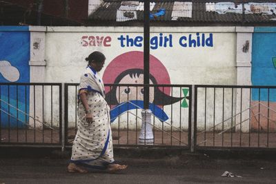 Rear view of man against graffiti wall