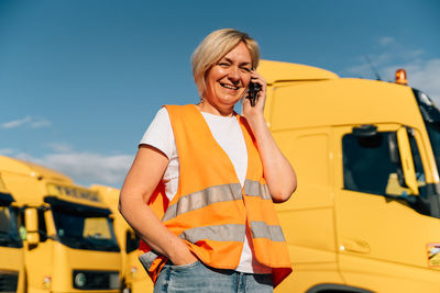 Happy driver talking on mobile phone in front of truck