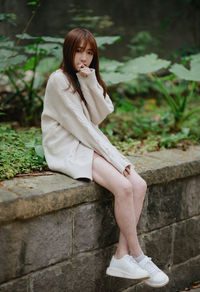 Portrait of young woman sitting on footpath